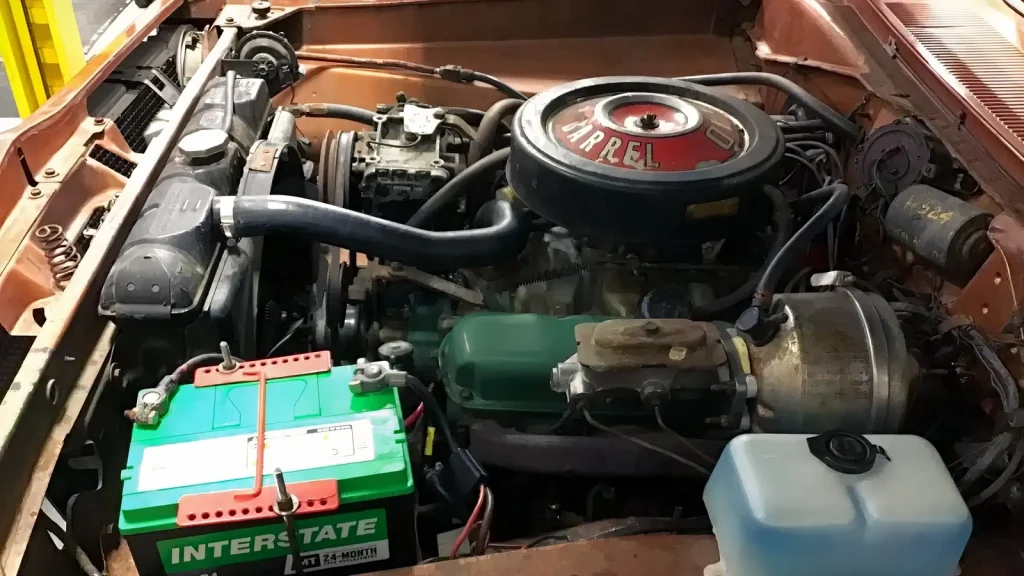 Compartiment moteur d'une Plymouth Barracuda 1969 avec V8, filtre à air rond et batterie verte