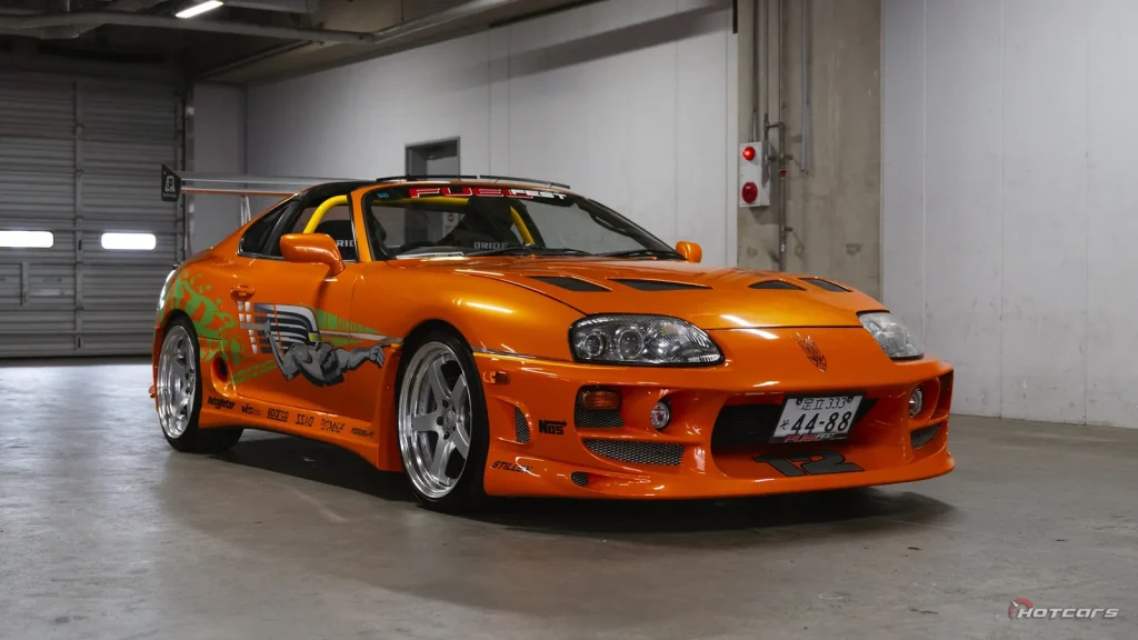 Réplique orange de la Toyota Supra de Fast and Furious avec décoration verte, garée dans un garage
